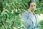 Femme d'affaires permanent dans la végétation, à l'aide de téléphone portable