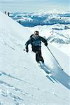 Skier skiing downhill, high angle view, mountains in background