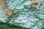 Woman pointing to map and holding compass, close-up, grass in foreground