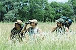 Hikers standing in field, one looking through binoculars