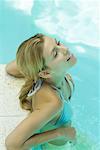 Young woman in pool, resting elbows on edge of pool