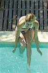 Junge Frau sitzt am Rand des Pools, Spritzwasser