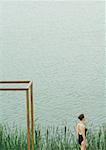 Jeune femme en état de maillot de bain de bord de l'eau, près de structure carrée