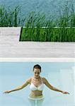 Young woman standing waist deep in pool