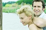 Couple by lake, man's arm on woman's shoulders