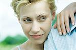 Woman leaning hand and head on man's shoulder, close-up