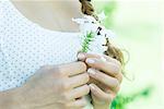 Woman holding flower, close-up of hands and chest