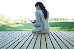 Businesswoman sitting on decking, writing