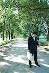 Businessman standing in rural road, holding briefcase and cell phone