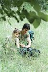 Hiking couple opening backpack in grass