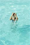 Jeune femme, projections d'eau sur le visage en piscine