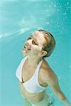 Young woman standing under spray of water in pool