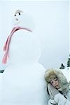 Teen girl resting head against snowman