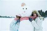 Two friends hugging snowman