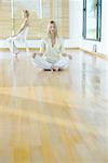 Group meditation, woman sitting on floor while second woman sits in chair