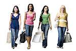 Four women walking and smiling with shopping bags