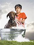 Boy bathing dog outdoors