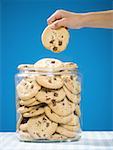 Hand grabbing chocolate chip cookie from jar