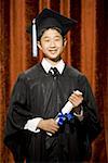 Boy graduate with mortar board and diploma smiling with braces