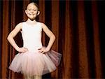 Fille ballerine sur scène avec les mains sur les hanches souriant