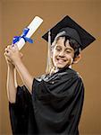 Boy graduate with mortar board and diploma smiling