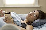 Woman lying in bed eating chocolate ice cream