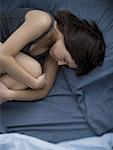 Frau im Bett schlafen zusammenrollen