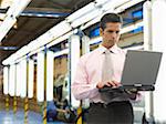 Man Using Laptop in Automotive Plant