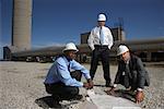 Businessmen Looking at Blueprint Outside of Factory