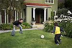 Father and Son Playing Soccer in Yard