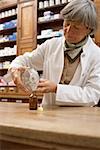 Female pharmacist filling medicine in a bottle