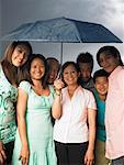 Family Standing together Under Umbrella