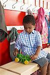 Boy Playing with Toy by Daycare Coat Rack