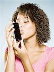 Adolescente baiser un téléphone intelligent avec les yeux fermés