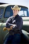 Homme au chapeau de cowboy se penchant sur camion souriant