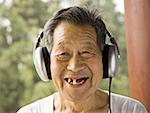 Toothless man with headphones outdoors smiling