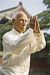 Man standing outdoors doing Kung Fu with ear buds and pagoda in background