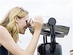Profile of woman looking through coin operated binoculars smiling