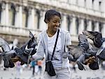 Woman in public square with pigeons smiling