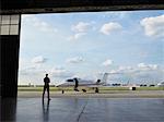 Technician in hangar looking at private jet on tarmac.