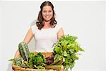 Jeune femme avec grand panier de légumes biologiques.