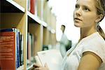 Young woman looking at shelves of books in library
