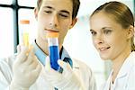 Young male and female scientists holding up test tubes