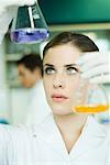 Young woman in research lab, holding up two flasks