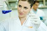 Jeune femme travaillant dans un laboratoire scientifique, brandissant des flacons