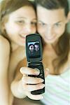Teenage girl photographing self with friend using cell phone