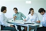 Business associates seated at table, chatting, three quarter length