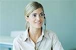 Young businesswoman wearing headset, smiling, head and shoulders