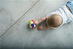 Baby crawling on floor, holding ball, view from directly above