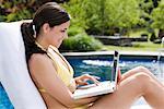 Woman Using Laptop by Pool